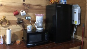Una cocina con un refrigerador negro, una cafetera y un microondas en la encimera.