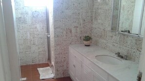 A bathroom with a shower, a sink, and a mirror. - Maria Izabel (Salvador)