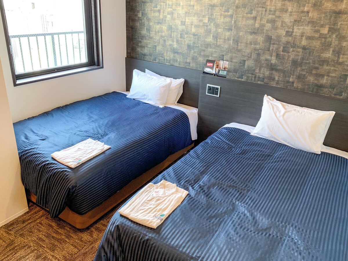 Two single beds with blue bedding, white pillows, and a wooden headboard.