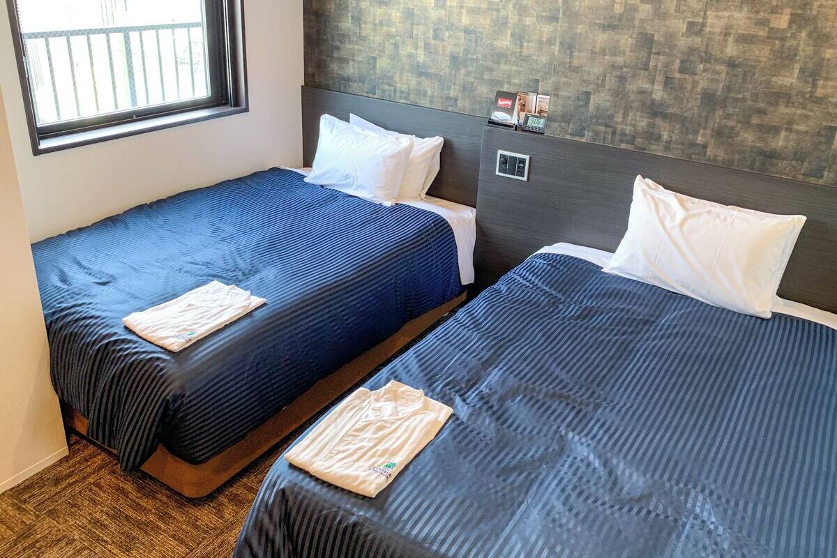 Two single beds with blue bedding, white pillows, and a wooden headboard.