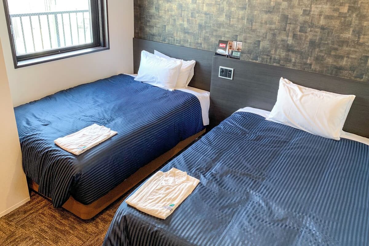Two single beds with blue bedding, white pillows, and a wooden headboard.