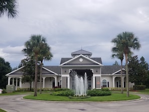 A large building with a central fountain, surrounded by palm trees and a well-maintained lawn.