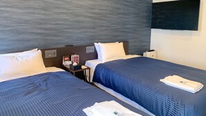 A hotel room with two beds, a flat-screen TV mounted on the wall, and a small table with a lamp. - Hotel Livemax Tokyo Kanda East (Tokyo)