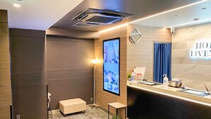 A modern hotel reception area with a digital display, a reception desk, and a seating area. - Hotel Livemax Tokyo Kanda East (Tokyo)