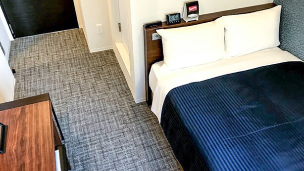 A hotel room with a bed, a nightstand, a digital clock, and a thermostat. - Hotel Livemax Chiba Sogaekimae (Chiba)