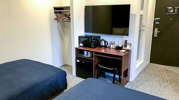 Habitación de hotel con dos camas, un escritorio, televisión, cafetera y teléfono.