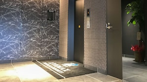 A modern elevator with a marble wall and a patterned wall panel. - Hotel Livemax Chiba Sogaekimae (Chiba)