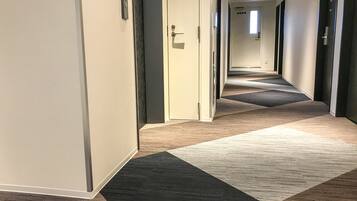 Un pasillo de hotel con pisos alfombrados y puertas que dan a las habitaciones.