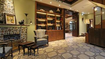 A cozy living room with a stone fireplace, a wooden bookshelf, and a patterned floor.