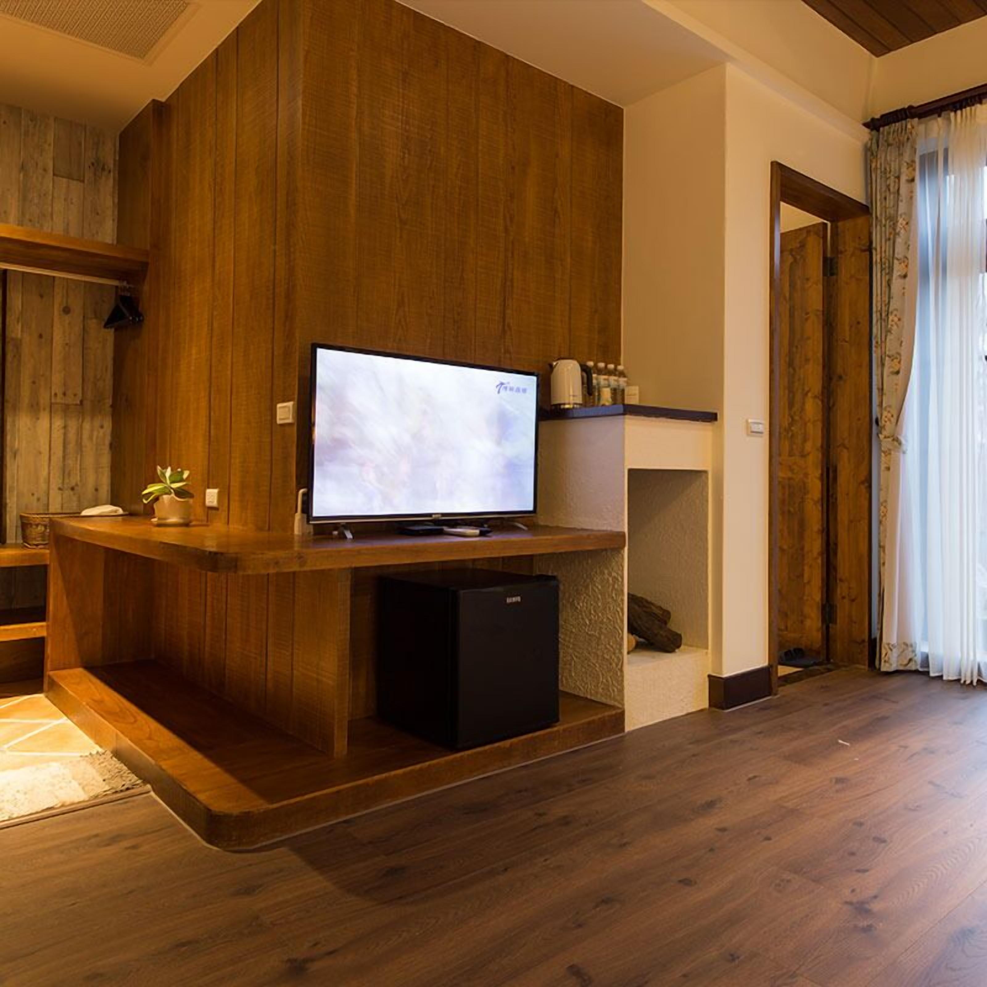 A modern living room with a wooden entertainment unit, a flat-screen TV, and a small black speaker.