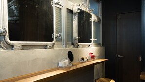 A bathroom with a wooden vanity, two mirrors, a small stool, and a door. - HARE-TABI SAUNA&INN YOKOHAMA (Yokohama)
