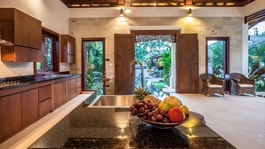A kitchen with wooden cabinets, a granite countertop, and a bowl of fruit.