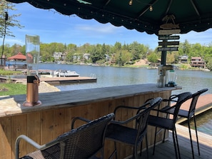 Eine Holzterrasse mit Barbereich mit Blick auf einen See, ausgestattet mit einem Mixer und einer Kaffeemaschine.