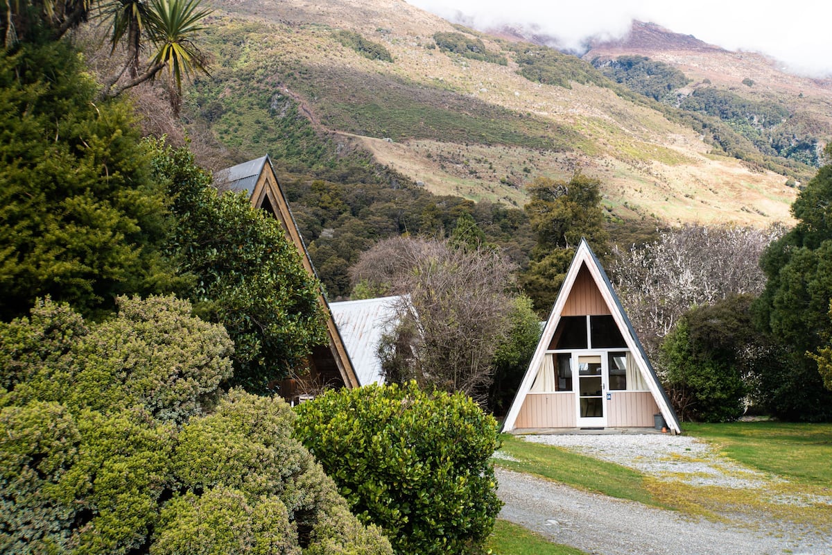 A small, triangular-shaped building surrounded by lush greenery and hills.