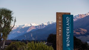 Un cartello in legno con la scritta "WONDERLAND MAKARORA LODGE" e simboli che indicano servizi come Wi-Fi, ristorante e bar.