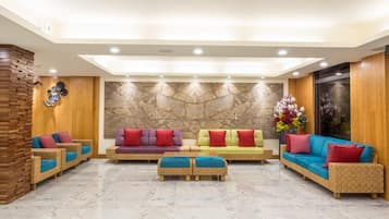 A spacious lobby with multiple seating areas, a decorative wall, and a large window.