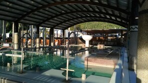 An outdoor swimming pool with a covered area, surrounded by buildings and a natural landscape. - Dong Tair Spa Hotel (Taimali)