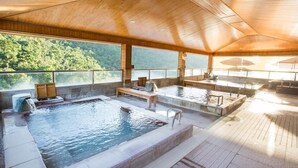 Piscina interna con soffitto in legno e ampie finestre affacciata su una zona boschiva.