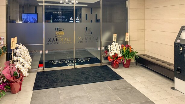 A hotel entrance with a glass door, a reception desk, and potted plants. - HOTEL LiVEMAX Nihonbashi Koamicho (Tokyo)