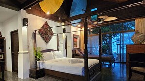 Ein modernes Schlafzimmer mit einem Himmelbett, einem großen Fenster mit Blick auf Bäume und einem Deckenventilator.