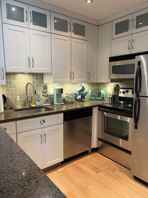 A modern kitchen with white cabinets, stainless steel appliances, a dishwasher, and a microwave. - >>Exceptional Updated Condo w Waterfront Views All Rooms-Walk to Town, Ferry<< (Port Clinton)