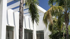 A modern building with large glass doors, a covered patio, and a well-maintained lawn.