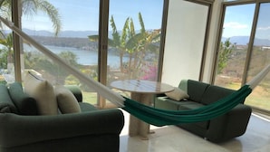 A room with a green sofa, a small round table, and a hammock.