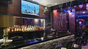 A bar area with a TV screen, a variety of liquor bottles, and a DJ setup. - Secrets Pattaya (Pattaya)