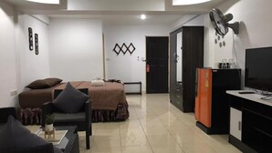 A modern hotel room with a bed, a sofa, a TV, and a minibar. - Secrets Pattaya (Pattaya)