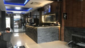 A modern bar area with a black countertop, a TV screen, and a stone wall. - Secrets Pattaya (Pattaya)