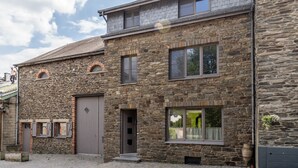 Un bâtiment en pierre doté d’un grand portail de garage, de nombreuses fenêtres et d’une allée d’entrée pavée.