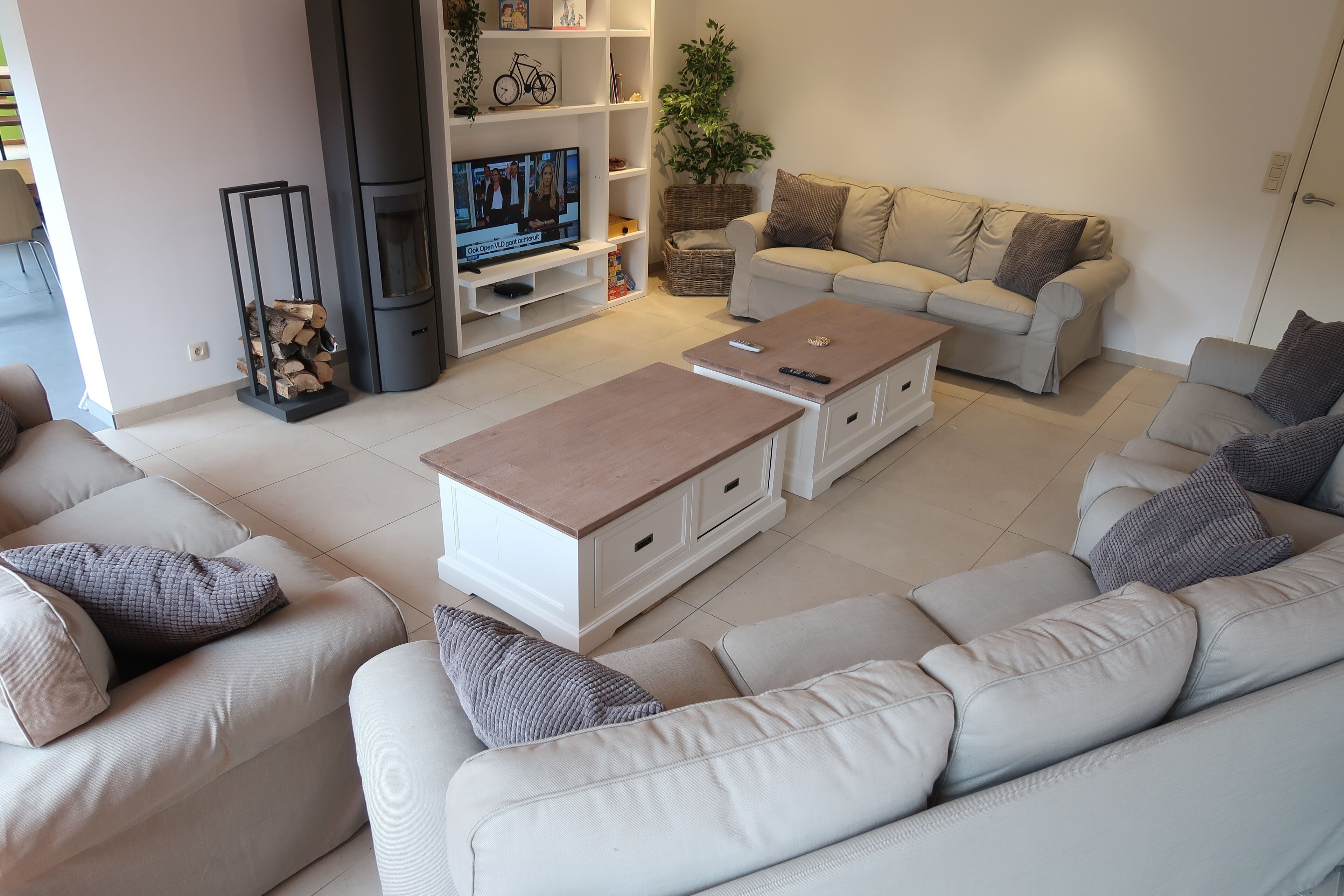 Un salon moderne avec un canapé beige, un canapé blanc et une table basse en bois. On y trouve un téléviseur posé sur un meuble et une cheminée.
