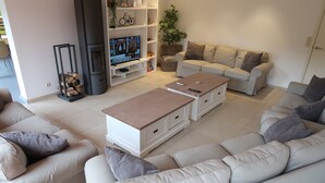Un salon moderne avec un canapé beige, un canapé blanc et une table basse en bois. On y trouve un téléviseur posé sur un meuble et une cheminée.