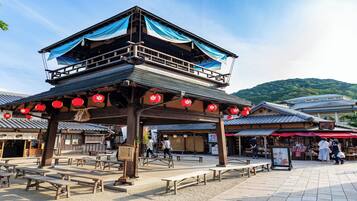 A traditional Japanese building with a wooden structure, outdoor seating, and red lanterns.