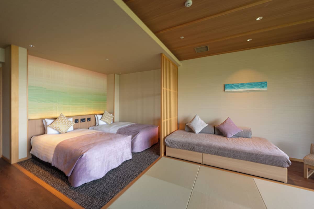 Habitación de hotel con dos camas, techo de madera y vista al mar.