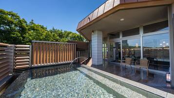 A modern building with a glass facade, a pool area with clear water, and outdoor seating.