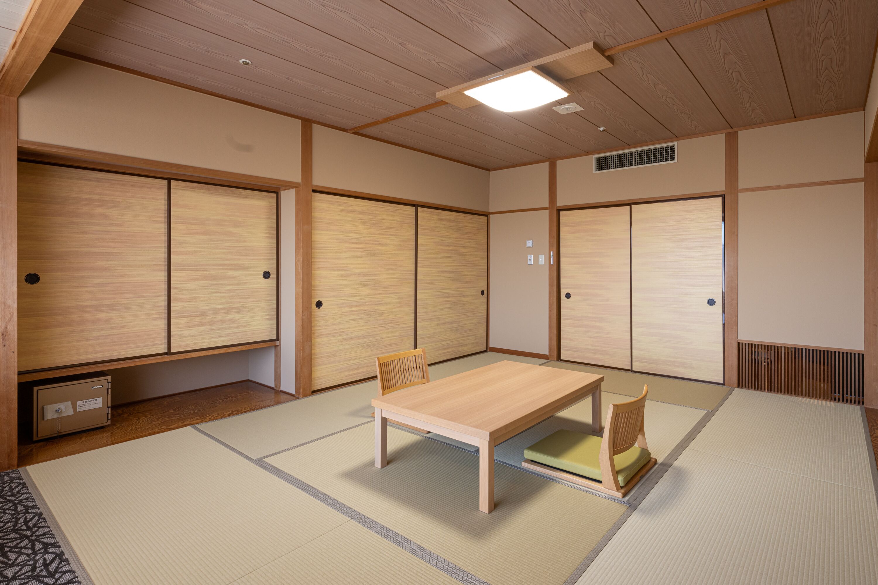 A traditional Japanese room with tatami flooring, a low wooden table, two chairs, and sliding doors.