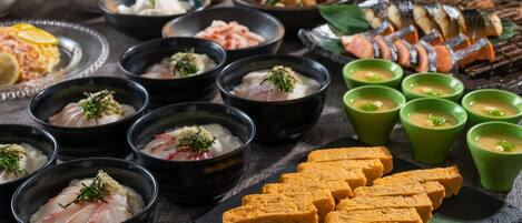 Une variété de plats, notamment des sashimis, du tofu et des sushis, présentés sur une table en bois.
