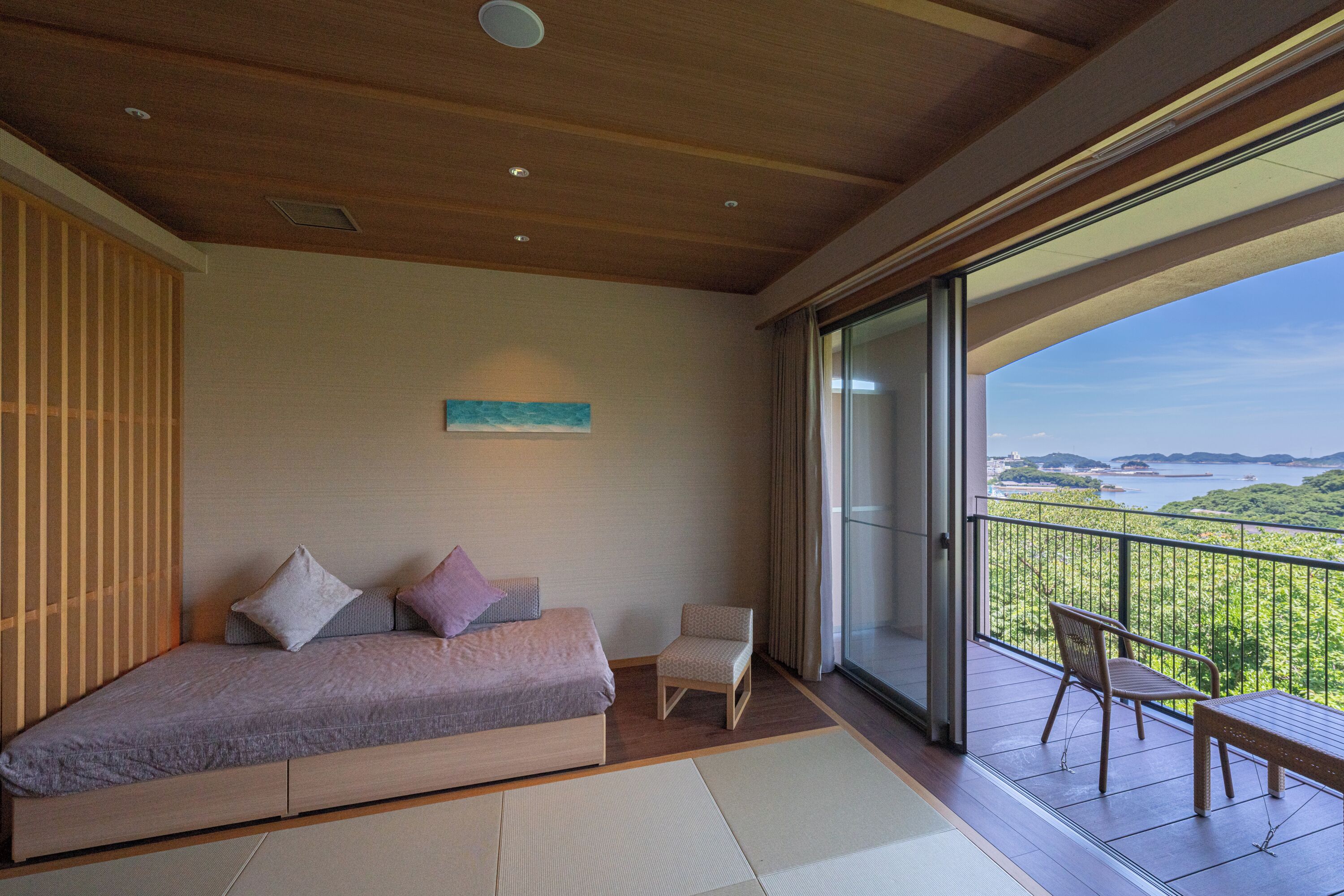 Un dormitorio moderno con una cama grande, una silla pequeña y un balcón con vistas.