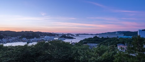 A coastal cityscape with buildings, a river, and hills.