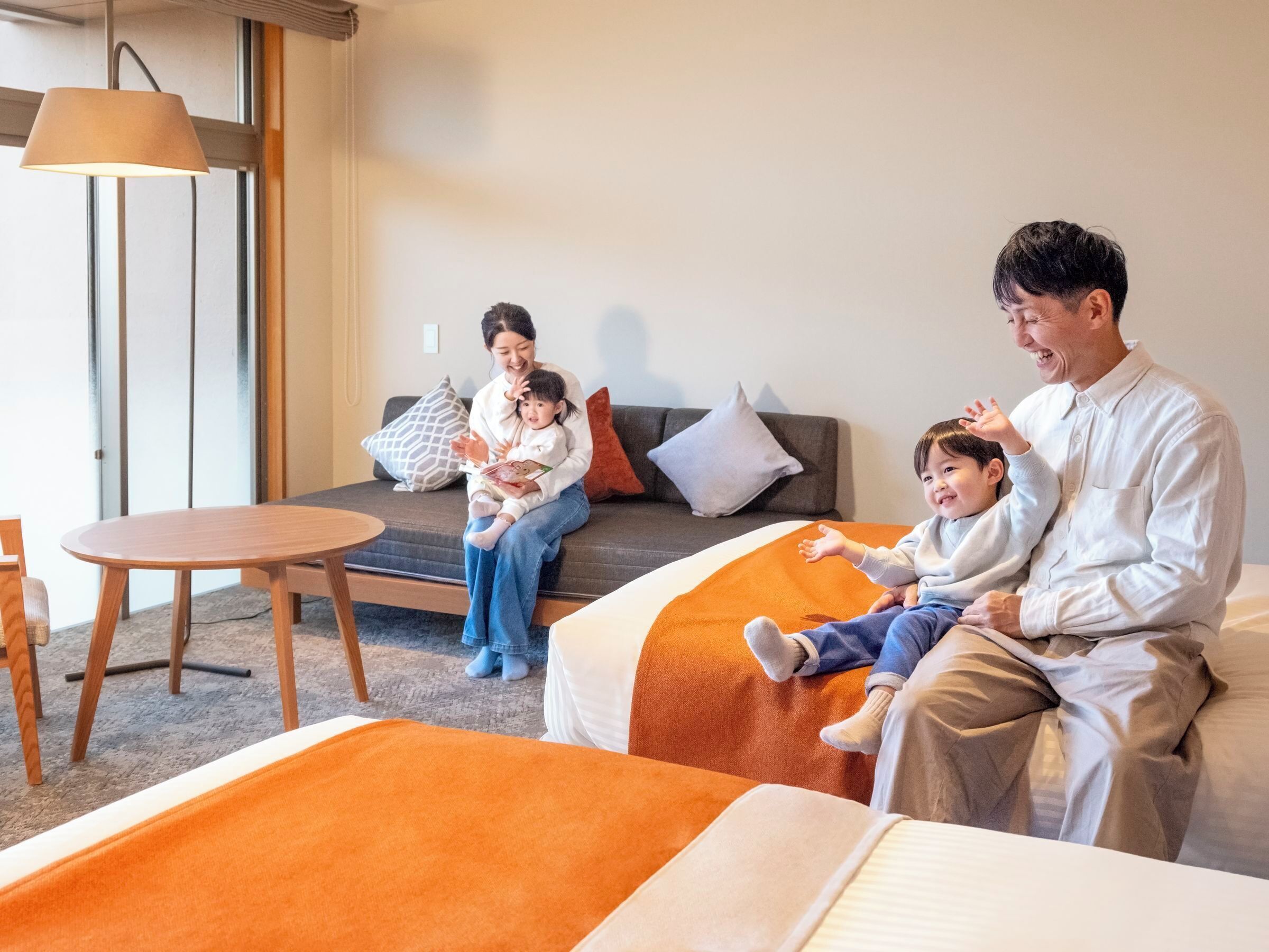 Habitación de hotel con sofá, una mesa redonda y una cama con ropa de cama naranja.