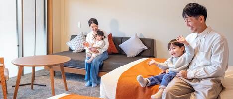 Habitación de hotel con sofá, una mesa redonda y una cama con ropa de cama naranja.
