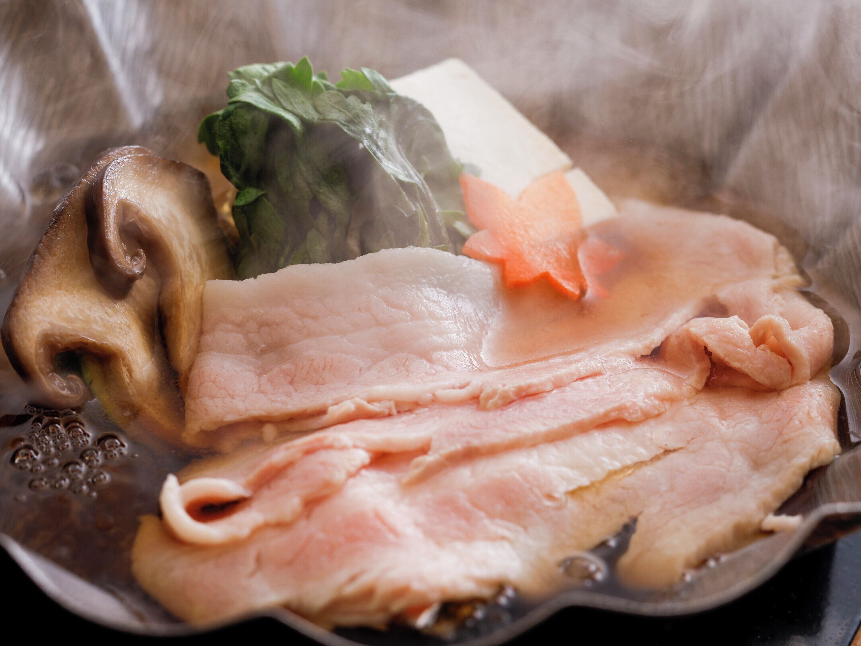 A hot pot with various ingredients like meat, vegetables, and tofu.