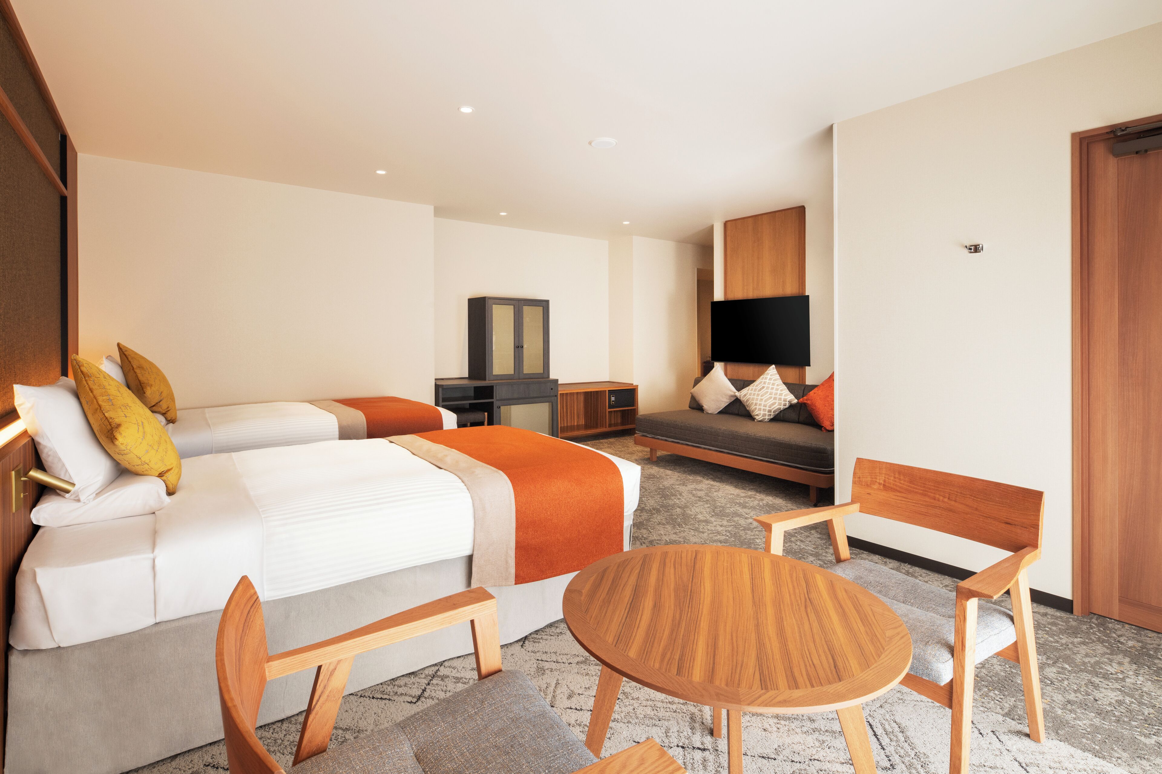A hotel room with a bed, a sofa, a TV, a desk, and a chair.