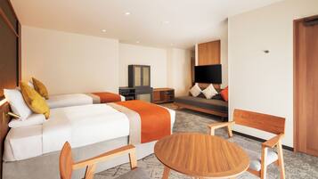 A hotel room with a bed, a sofa, a TV, a desk, and a chair.