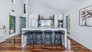 A modern kitchen with a central island, bar stools, and a large window. - Mandalay Escape Serenity and Pool (Mandalay)