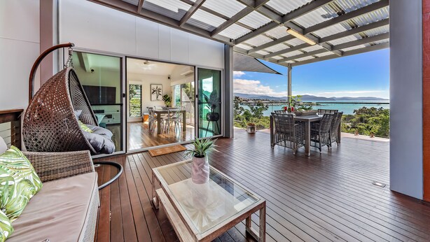 A modern outdoor deck with a glass table, wicker seating, and a view of the ocean. - Mandalay Escape Serenity and Pool (Mandalay)