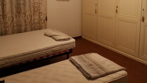 Ein Schlafzimmer mit Bett, Nachttisch, Pendelleuchte, Kleiderschrank und einem Wandbild.
