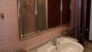 Ein Badezimmer mit einem Doppelwaschbecken, einem Spiegel mit goldener Rahmung und Wandfliesen mit Muster.