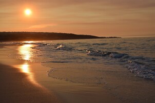 Una playa con olas y un atardecer.